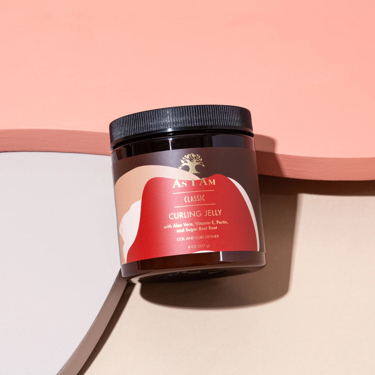 A brown plastic can with a label stands on a pink background. It contains As I Am Curling Jelly and has a picture of a tree on the label.