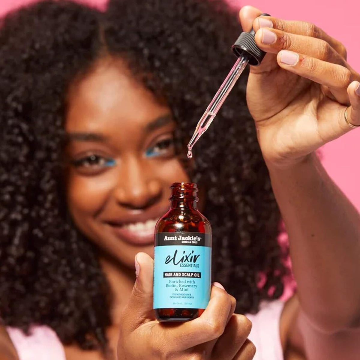 Close-up of a hand holding Aunt Jackie's Elixir Biotin Rosemary Hair and Scalp Oil.