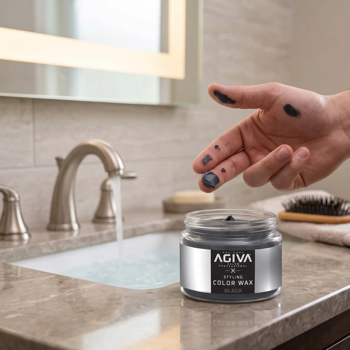 AGIVA Styling Color Wax Black in open glass jar on bathroom table, hand with black colored fingers from adult.