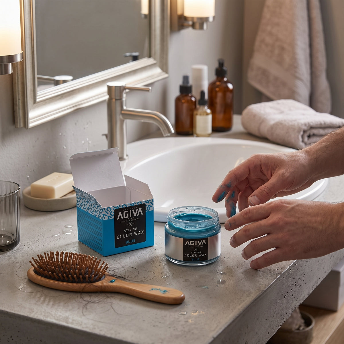 Agiva Styling Color Wax Blue in open glass jar on bathroom table with hands dyed blue and hairbrush.