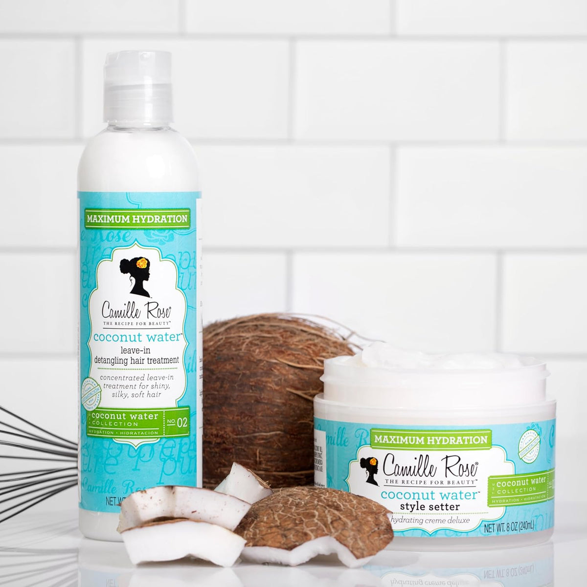 White bottle of Camille Rose Coconut Water Leave-In Treatment and jar of Style Setter next to a whole and pieces of a coconut.