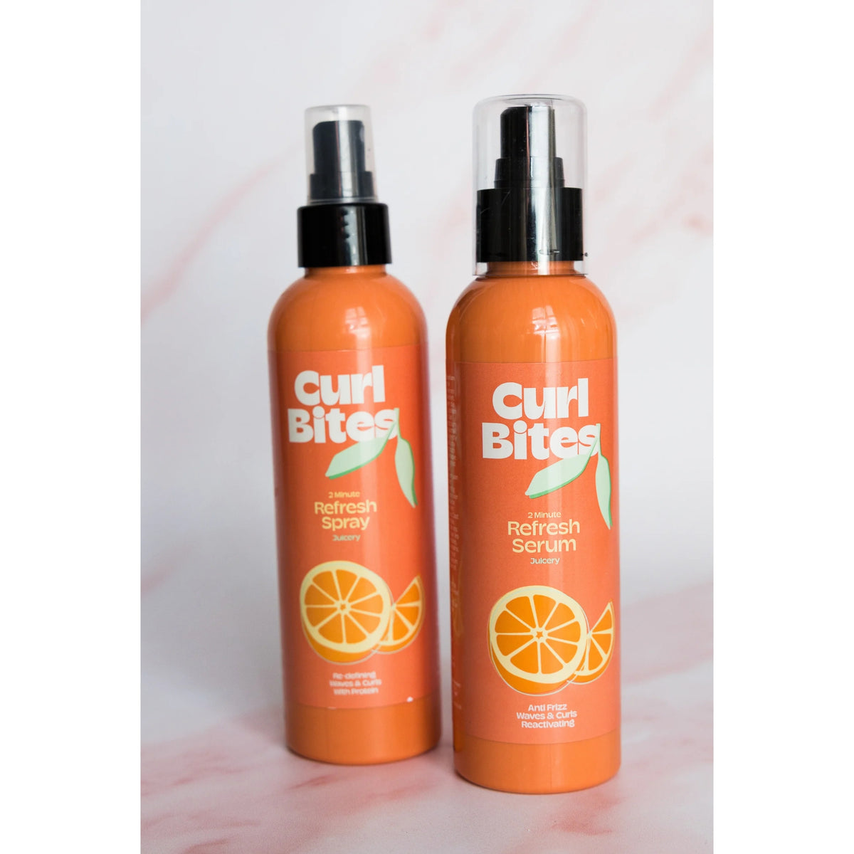 Two orange Curl Bites bottles: 2 Minute Refresh Spray and Refresh Serum with an orange motif.