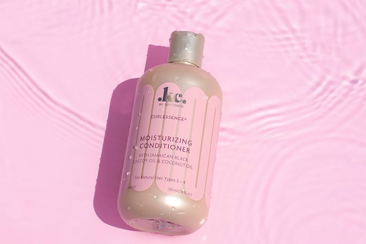 Keracare Curlessence Moisturizing Conditioner against a pink background with water reflections.