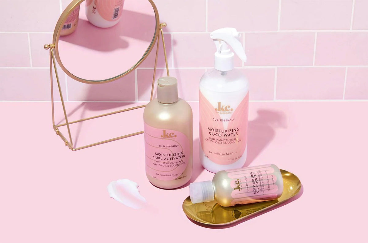 Keracare Curlessence Moisturizing Curl Activator, Coco Water and Oil Cocktail presented on a pink background with a mirror.