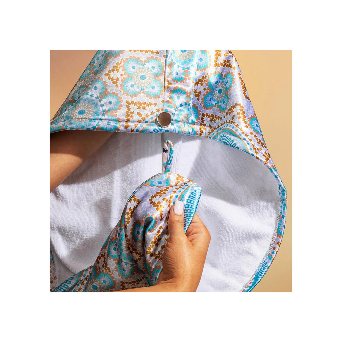 Hands folding Bounce Curl Satin Microfiber Turban with white inside and colorful pattern in blue, gold and brown.